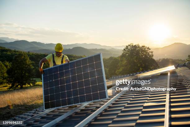 technician fitting solar panels to a house roof. - painel solar imagens e fotografias de stock