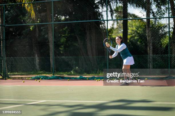 asiatische chinesin, die am wochenendmorgen auf dem tennisplatz übt - tennis court and low angle stock-fotos und bilder