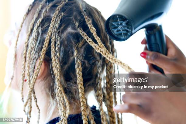a young woman having her hair braided - gekrepptes haar stock-fotos und bilder