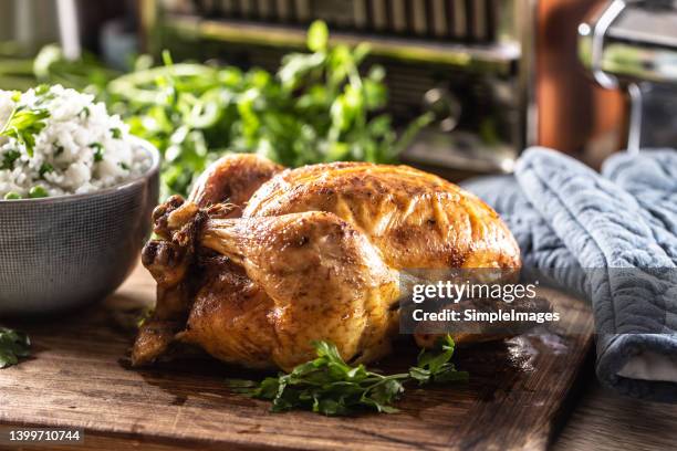 crispy and juicy golden baked chicken served whole on a table with rice. - roast chicken table stockfoto's en -beelden