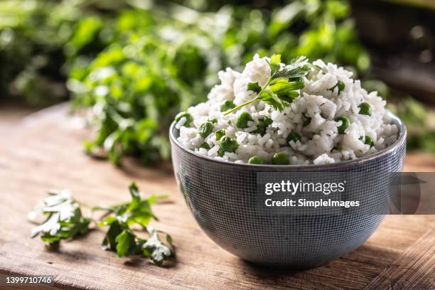 freshly steamed rice served in grey bowl with peas and fresh parsley leaves on top. - basmati rice stock-fotos und bilder
