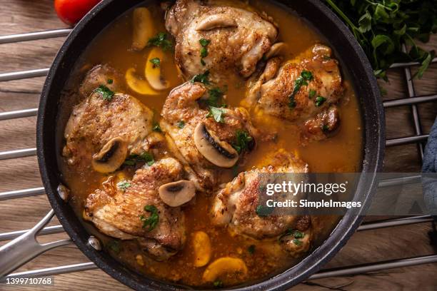 top view of chicken thighs with bones cooked with mushrooms in a rich sauce, served in a pan. - stew fotografías e imágenes de stock