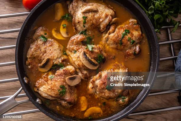 top view of chicken thighs with bones cooked with mushrooms in a rich sauce, served in a pan. - comfort food stock pictures, royalty-free photos & images