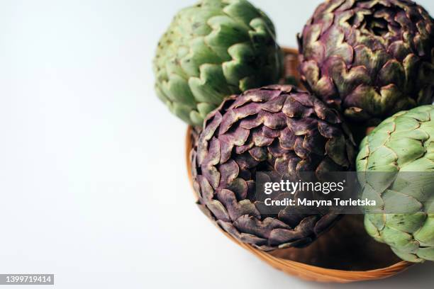 green and purple artichoke in a wicker basket. exotic vegetable. healthy food. farm harvest. dish ingredient. - cabbage flower stock pictures, royalty-free photos & images