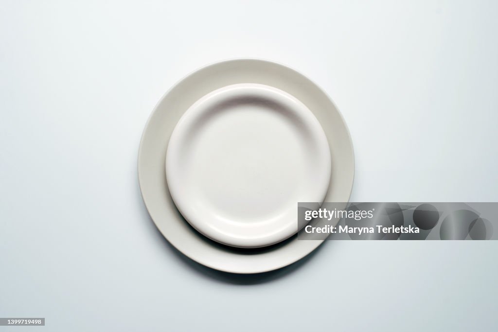 A white-gray plate lies on a white background. Minimalism. Empty plate for food. Culinary background.