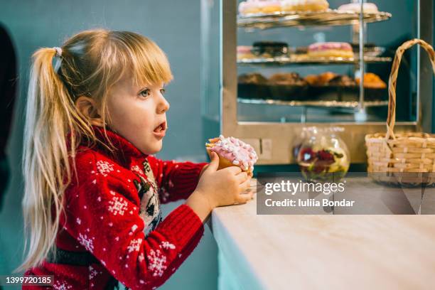 little girl eating a donut in a cafe - fat people eating donuts foto e immagini stock