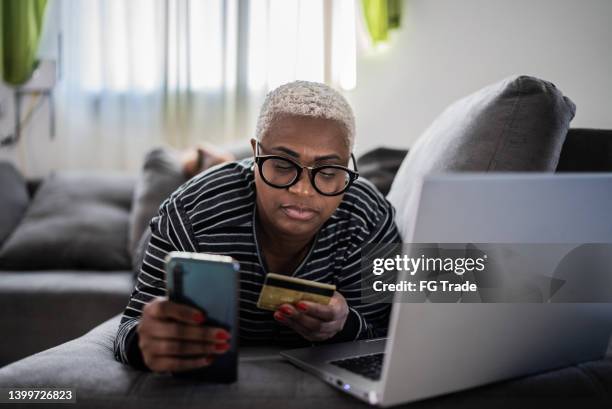 mujeres maduras que compran en línea usando el teléfono móvil en casa - chubby credit fotografías e imágenes de stock