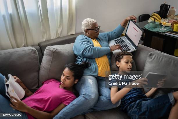 familie zusammen auf dem sofa zu hause - homemaker stock-fotos und bilder