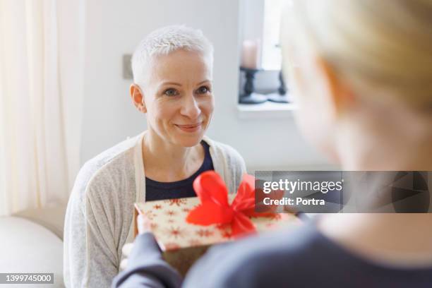 mother receiving a present from her daughter at home - giving a girl head stock pictures, royalty-free photos & images