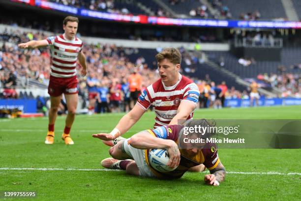 Chris McQueen of Huddersfield Giants scores their side's second try whilst under pressure from Ethan Havard of Wigan Warriors during the Betfred...