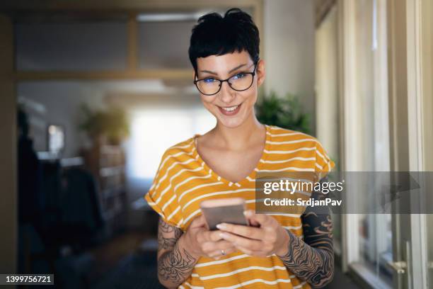 porrait de joven caucásica, con el pelo corto usando el teléfono móvil - hipster fotografías e imágenes de stock