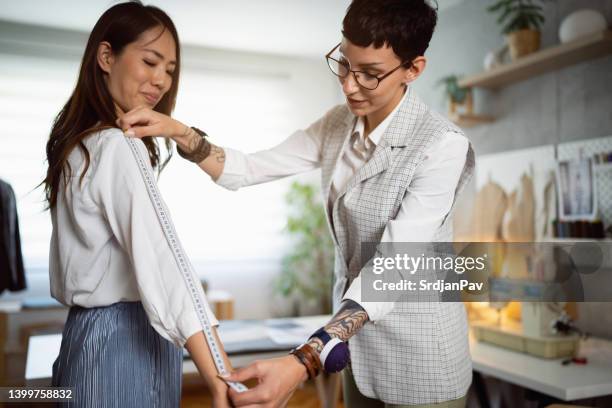 caucasian female tailor, taking measures of the female client - tailor stock pictures, royalty-free photos & images