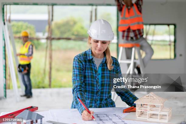 female architect looking at blueprints on construction site - attic conversion stock pictures, royalty-free photos & images