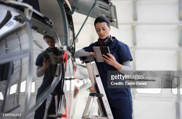 female aero engineer working on helicopter in hangar - aviation engineering stockfoto's en -beelden