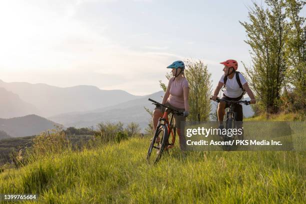mountain biking couple relax in grassy meadow - het einde stockfoto's en -beelden