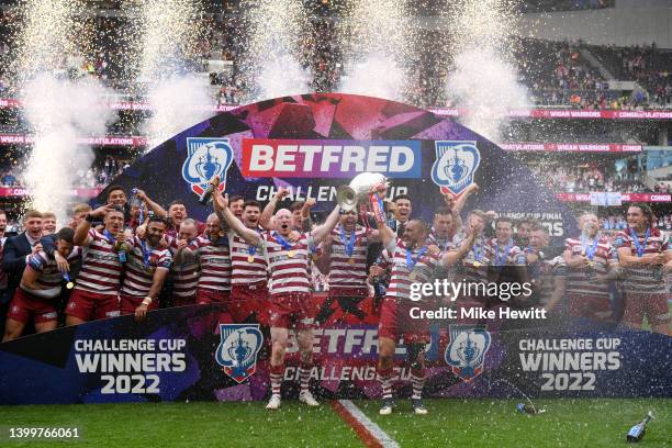 Liam Farrell and Thomas Leuluai of Wigan Warriors lift the Betfred Challenge Cup as their side celebrates after victory in the Betfred Challenge Cup...