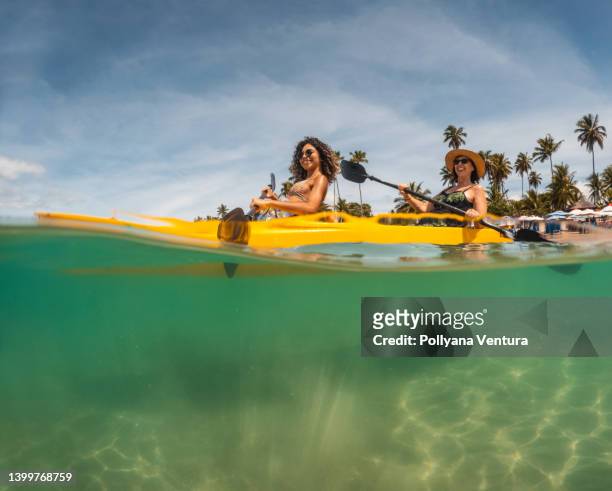 turisti pagaiando kayak sulla spiaggia - kayaking foto e immagini stock