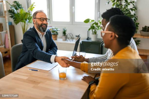 grateful black family couple handshake with insurer before signing contract - actuaries stock pictures, royalty-free photos & images