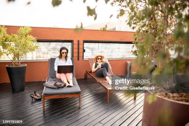 due giovani imprenditrici che lavorano all'aperto sulla terrazza di un hotel - sedia a sdraio foto e immagini stock