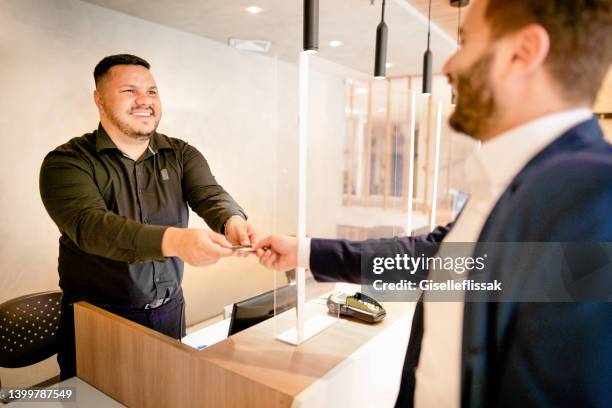 concierge helping a businessman check-in to a hotel during a business trip - concierge stock pictures, royalty-free photos & images