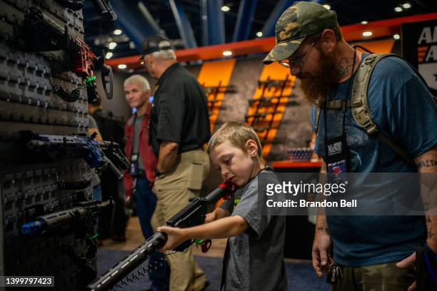 Chris Shelton oversees his son Luke Shelton as he steadies an AR-15 rifle at the George R. Brown Convention Center during the National Rifle...