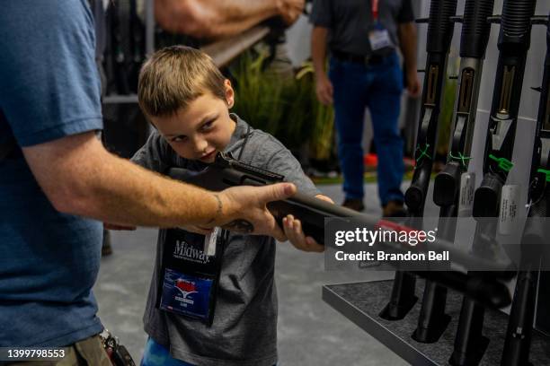 Chris Shelton helps his son Luke Shelton steady a firearm at the George R. Brown Convention Center during the National Rifle Association annual...