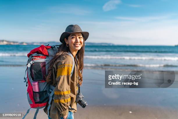 young female traveller enjoying spending time at beach on her vacation - asian tourist bildbanksfoton och bilder