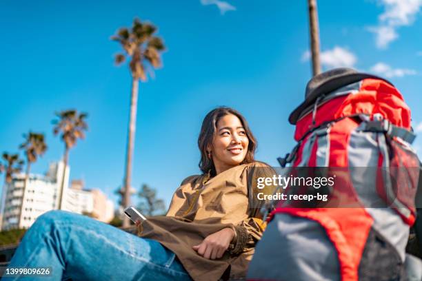 young female traveller using smart phone while enjoying her vacation - solo travel stock pictures, royalty-free photos & images