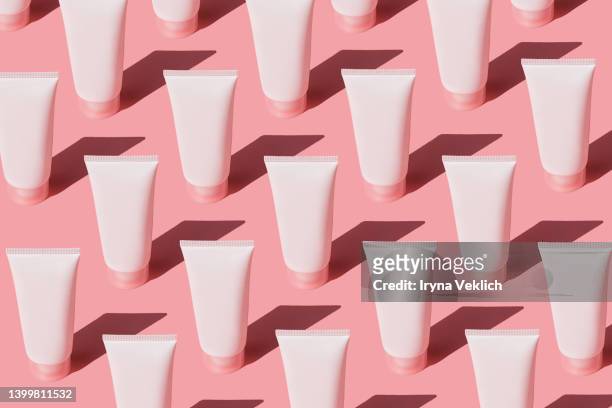 skin care pattern made with tubes with  beauty product facial cream or hand cream,  lotion, shampoo on pastel pink color background. - cream tube stock pictures, royalty-free photos & images