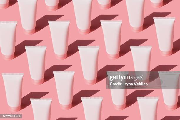 skin care pattern made with tubes with  beauty product facial cream or hand cream,  lotion, shampoo on pastel pink color background. - creme tube imagens e fotografias de stock