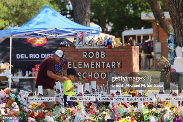 Man and a child pay their respects at a memorial to the victims of the Robb Elementary School mass shooting on May 28, 2022 in Uvalde, Texas....