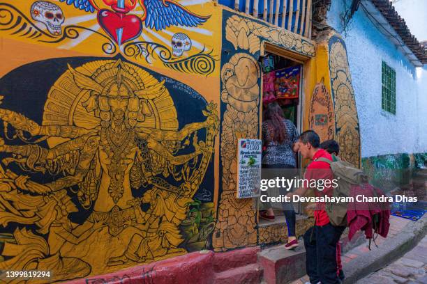 bogotá, colombia - a tourist on the colourful calle del embudo in the historic la candelaria of the capital city, studies a list displayed outside a store - calle del embudo stock pictures, royalty-free photos & images