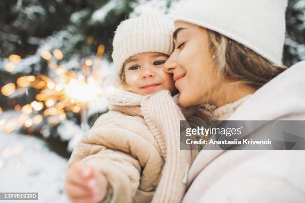 happy mother and daughter holding bengal lights and enjoying winter snowy nature. - child scarf stock-fotos und bilder