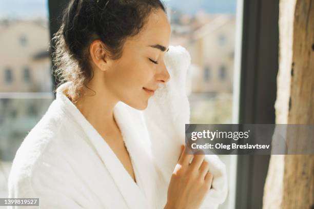 pretty woman cleaning her face in morning with white towel in bathroom. close up - gesichtsreinigung stock-fotos und bilder