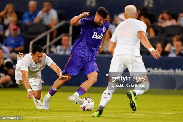 Lucas Cavallini of Vancouver Whitecaps controls the ball against Kortne Ford and Roger Espinoza of Sporting Kansas City during the second half at...