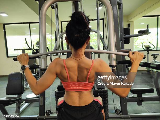 rear view of a woman exercising back muscles in the gym - sports india stock pictures, royalty-free photos & images