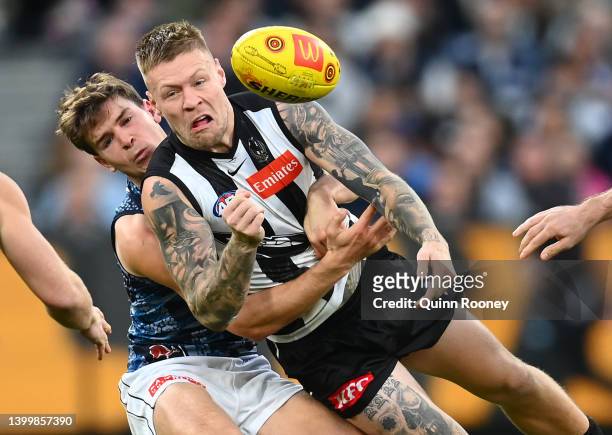 Jordan De Goey of the Magpies handballs whilst being tackled by Paddy Dow of the Blues during the round 11 AFL match between the Collingwood Magpies...