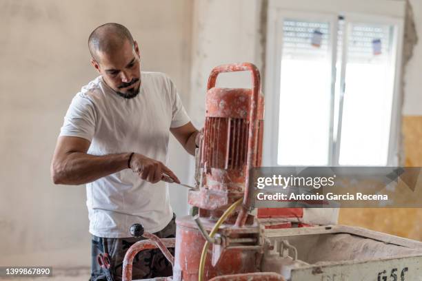 white plaster worker with machine to smooth walls and remove wall drips (gotelé) working on home renovations - lehm mineral stock-fotos und bilder