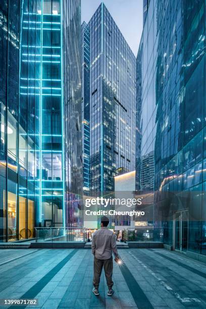 young man standing in front of contemporary financial skyscrapers - provinz shandong stock-fotos und bilder