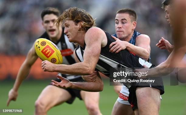 Nathan Murphy of the Magpies handballs whilst being tackled during the round 11 AFL match between the Collingwood Magpies and the Carlton Blues at...