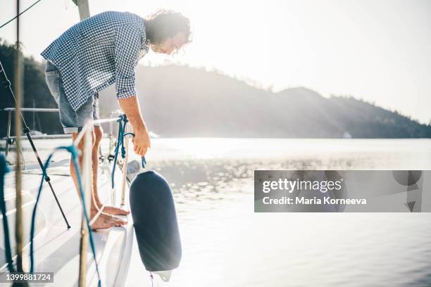 man hanging fender. - safe harbor stock pictures, royalty-free photos & images