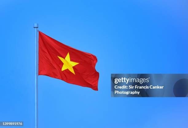 vietnamese national flag against clear blue sky with copy space in hanoi, vietnam - vietnam flag stock pictures, royalty-free photos & images