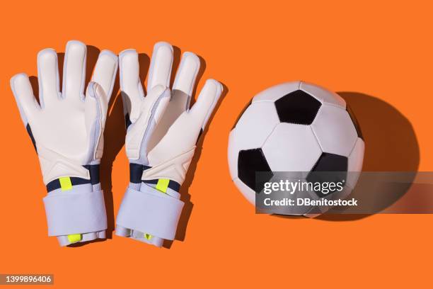 white goalkeeper and soccer ball gloves on orange background. concept of football, sports, competition and world champion. - sporthandschuh stock-fotos und bilder