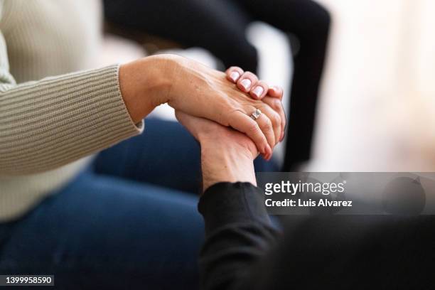 close-up of people holding hands in a support group session - gruppentherapie stock-fotos und bilder