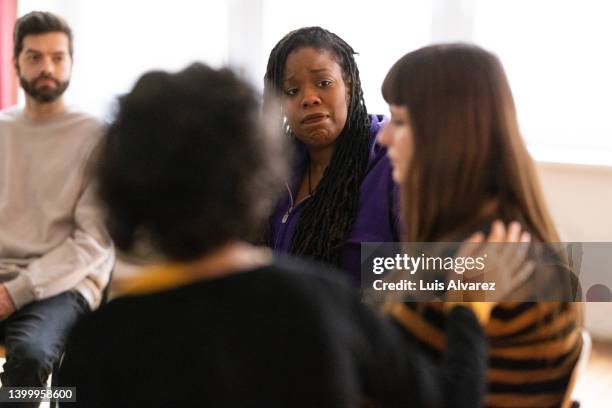 support group consoling and encouraging a woman during session - group therapy stock pictures, royalty-free photos & images