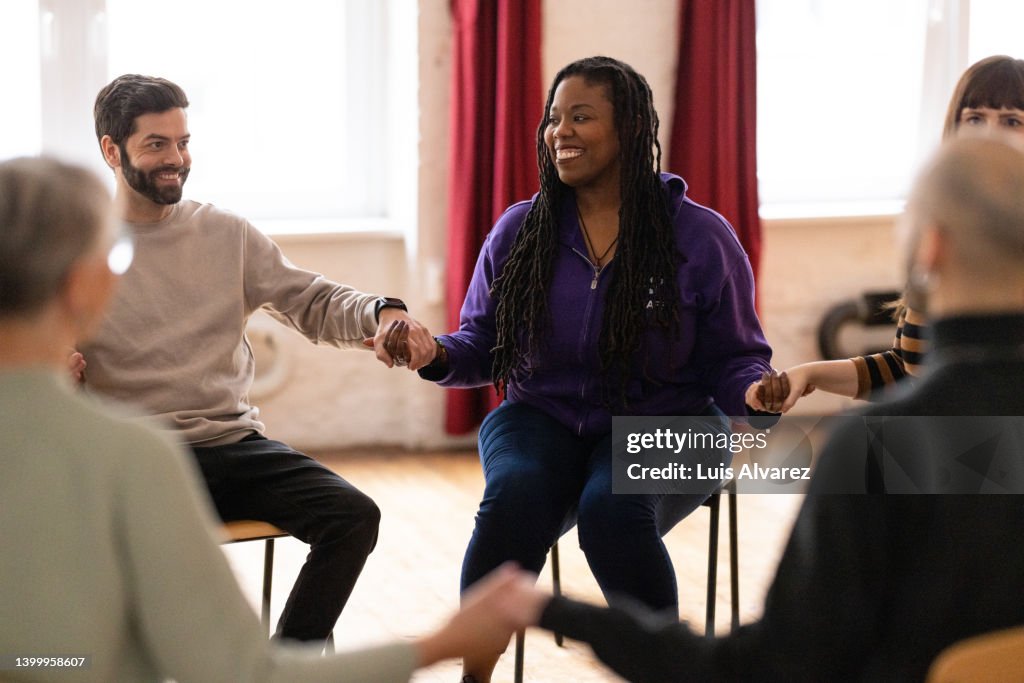Multiracial group of people holding hands during a group therapy session