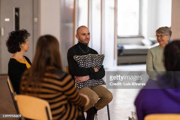 man holding a pillow and sharing his mental health problems with a support group - male victim stock pictures, royalty-free photos & images