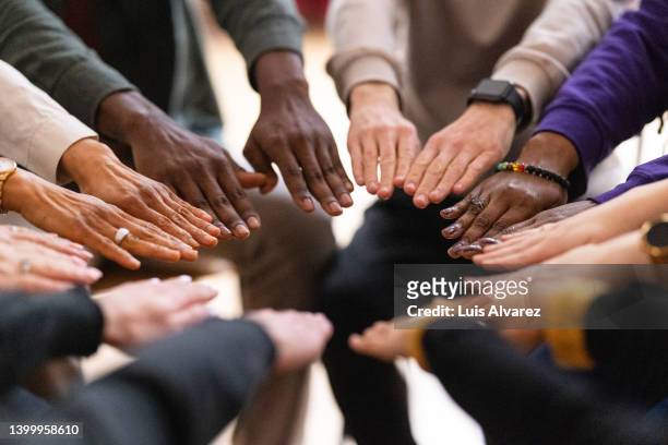 support group putting their hands together in circle - diverse huddle stock pictures, royalty-free photos & images