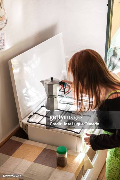side view of female with red hair preparing using old coffee machine to make fresh coffee while standing at cooker in domestic kitchen - old person kitchen food ストックフォトと画像