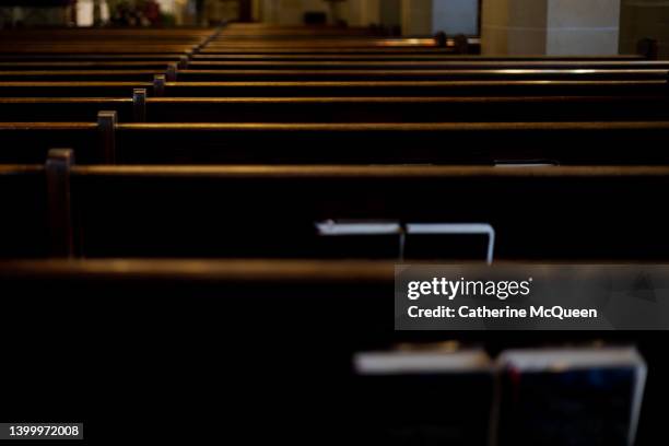 intersection of religion & politics: rear view of rows of wooden pews with religious liturgy books stored in pew racks in church - prediger stock-fotos und bilder